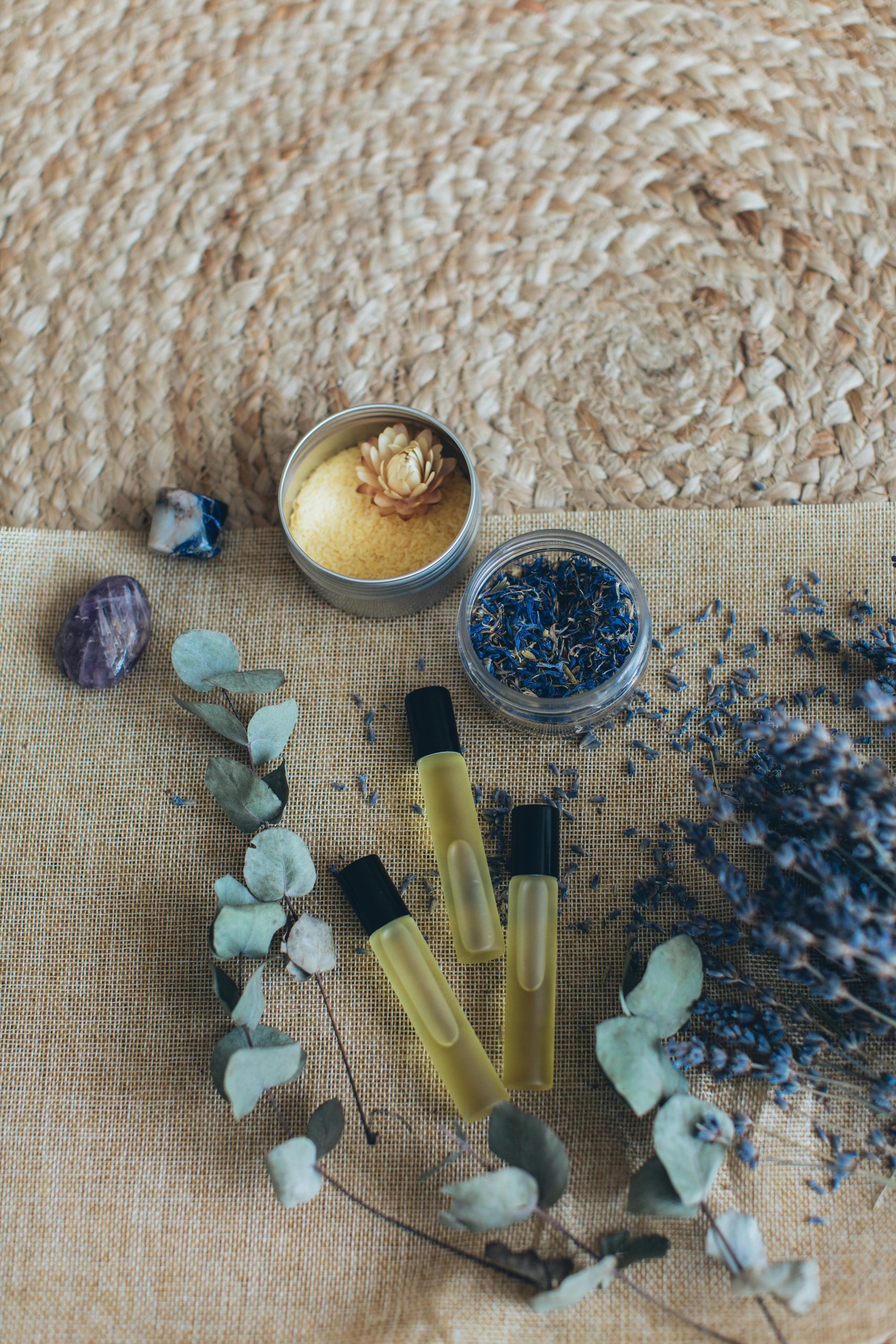 Top view of aromatherapy set with lavender, essential oils, and crystals on woven mat.